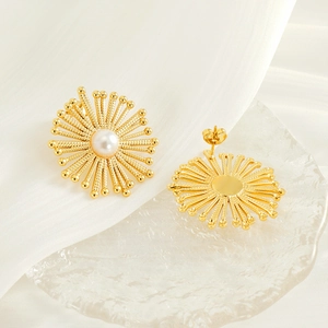 Macro detail of gold sunflower earrings with pearls on an elegant silk fabric background