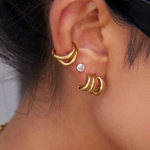 Detailed view of layered 14K gold stainless steel earrings and cuffs on model