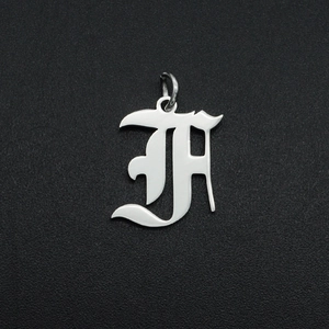 Macro shot of silver gothic letter H hollow pendant with metallic polished finish