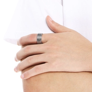 Detailopname van de zilveren metalen gestreepte ring aan vinger met geribbelde textuur