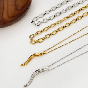 Italian horn pendant necklaces in gold and silver steel on a minimalist white surface