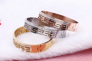 Close-up of Greek Key engraved bangles in gold, silver, and rose gold with pavé crystals