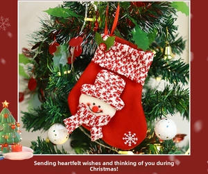 Detail view of a red Christmas stocking with snowman decor hanging on a festive tree