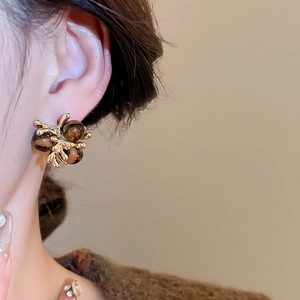 Close-up of vintage golden earrings with brown heart stones on model ear