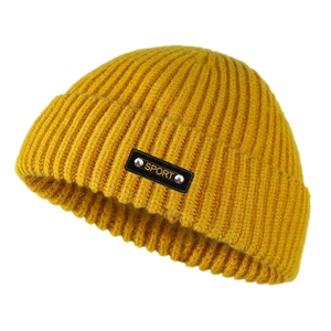 Dettaglio del berretto in maglia giallo zenzero con toppa in pelle SPORT e rivetti metallici