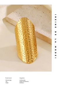 Detail of a wide gold hammered ring featuring a textured surface on a stone stand