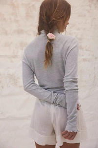 Rear view detail of gray waffle knit long sleeve top with ruffle trim and high collar
