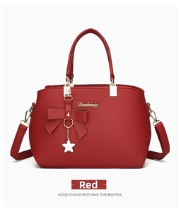 Close-up of red lychee pattern leather bag with metal logo, bow and floral charm