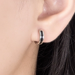 Chic silver hoop earrings with black enamel inlay worn by a model in a close-up shot