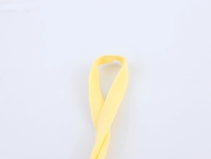 Détail de la sangle en tissu jaune avec coutures blanches sur la robe en mousseline
