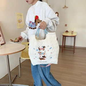Close-up of white quilted tote with cute cartoon dog embroidery and blue checkered handles