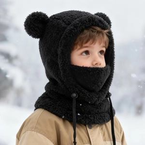 Détail de la cagoule enfant en peluche noire avec oreilles d'ours sur fond de neige
