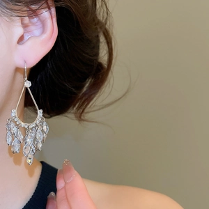 Detailed view of teardrop crystal tassel earrings with marquise-cut stones on model