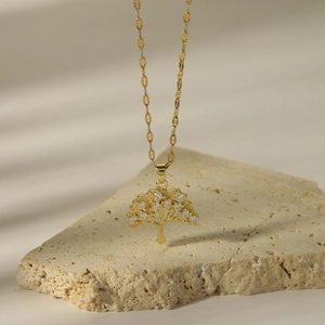 Gold life tree necklace with cubic zirconia on a decorative stone base