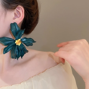 Detail of dark green acrylic flower earring worn by model for beach vacation style