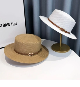 Detail of khaki and white flat straw hats with brown leather bands and gold buckles