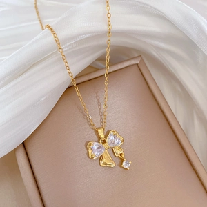 Elegant gold bow necklace with sparkling zircon crystals displayed on white silk fabric