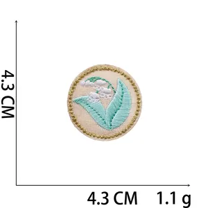 Detailed view of circular lily of the valley embroidery patch with golden edge and size details