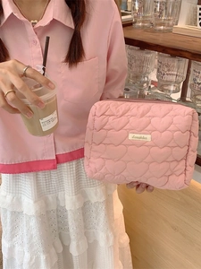 Pink heart quilted storage bag with zipper closure and logo tag held by a hand