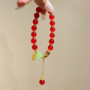 Détail du bracelet en agate rouge avec pendentif doré Fu et breloque en émail porte-bonheur