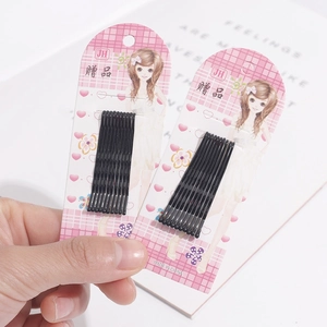 Close-up of black wavy bobby pins on pink display cards held in hand for hair styling