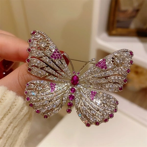 Detailed macro view of a silver butterfly brooch with red corundum and inlaid rhinestones