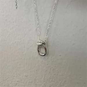 Close-up of minimalist 925 sterling silver knotted pendant necklace with fine cable chain