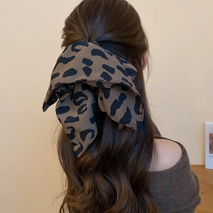 Dettaglio di un fermaglio per capelli con fiocco leopardato indossato da una modella