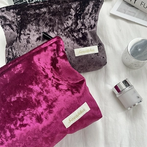 Detailed view of embossed velvet makeup bags with golden logo on soft white fabric