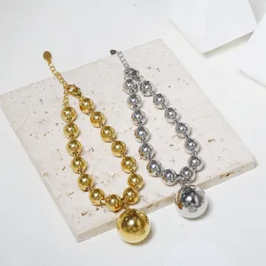 Polished 18K gold and silver hollow bead bracelets with ball charms on stone background