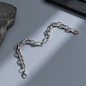 Detailed view of silver stainless steel curb chain bracelet with lobster clasp on rock