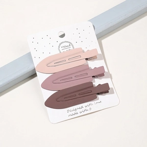Set of three matte duckbill hair clips in brown tones on a white display card