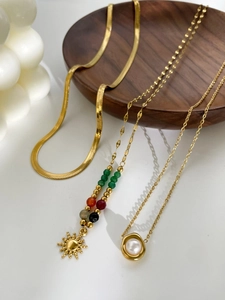 Mix of 18K gold snake chain and pearl pendant necklace on a wooden tray decor