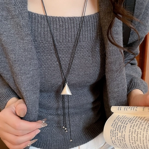 Detailed macro view of a silver-bordered triangular shell pendant with black cords
