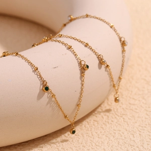 Detail of 18K gold-plated stainless steel layered necklace with green and white zircons