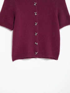 Detailed macro of rhinestone bow metal buttons on a soft knit burgundy cardigan sweater