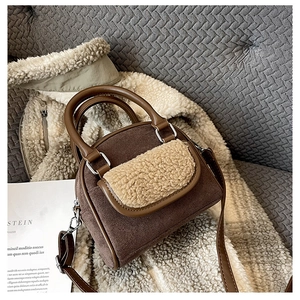 Detail of dark brown faux suede handbag with plush shearling trim and silver hardware