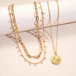 Detail of 18K gold plated layered necklace with sun coin pendant and pearl accents