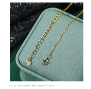 Macro detail of S925 sterling silver gold-plated lobster clasp and heart pendant tag