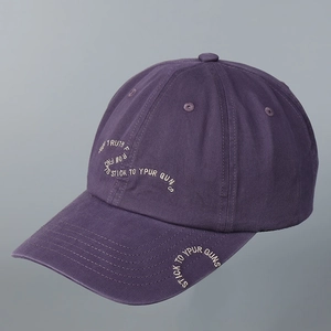 Detailed close-up of dark purple cotton baseball cap featuring white slogan embroidery
