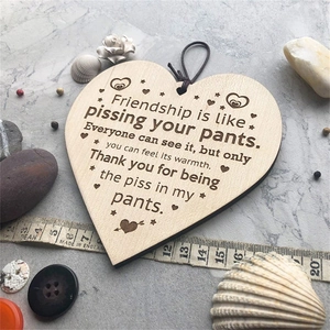 Detail of a heart-shaped wooden friendship plaque with humorous quote and rustic decor