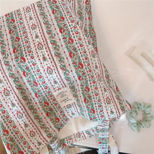 Nahaufnahme der Vintage-Leinentasche mit rot-grünem Blumenmuster auf weißer Oberfläche
