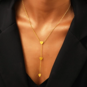 Elegante collana a Y dorata in acciaio inossidabile con tre ciondoli a cuore su una modella