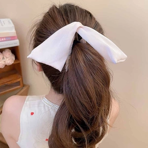 Détail d'un grand nœud en satin blanc pour cheveux porté sur une queue de cheval élégante