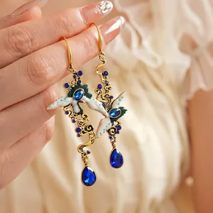 Vintage gold crane earrings with blue teardrop gemstones and enamel detailing