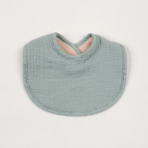 Close-up of the grey-green muslin cotton baby bib showing fine stitching and layered texture