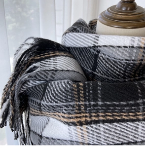 Close-up of thick plaid scarf featuring classic monochrome weave and delicate tassel fringe