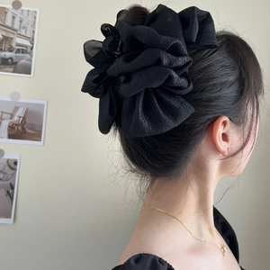 Detailed view of a black oversized mesh bow hair claw clip worn on a model's hair