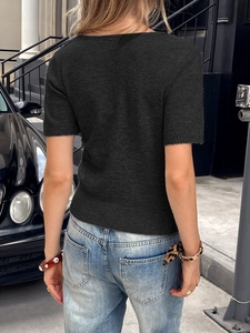 Détail du dos d'un t-shirt noir en maille à manches courtes porté avec un jean bleu chic