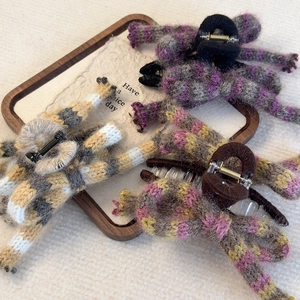 Flat lay of four colorful knitted stripe bow hair claws on a wooden tray with a card